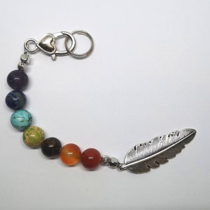 Può includere: Un portachiavi con perline arcobaleno, un ciondolo a forma di piuma argentata e una chiusura a forma di cuore argentata.
