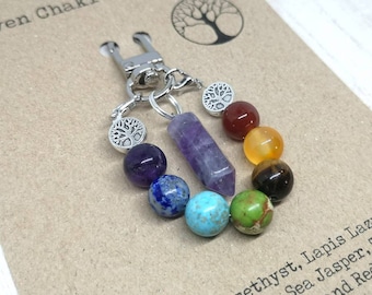 May include: A seven chakra keychain with a silver tree of life charm and a purple amethyst point. The keychain features seven beads in the colors of the chakras: purple, blue, turquoise, green, yellow, orange, and red.