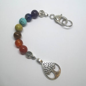 Può includere: Un portachiavi chakra arcobaleno con un ciondolo a forma di albero della vita argentato. Il portachiavi presenta sette perline che rappresentano i sette chakra, tra cui rosso, arancione, giallo, verde, blu, indaco e viola.