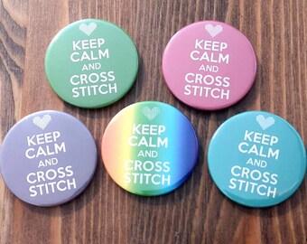 Może przedstawiać: Pięć okrągłych guzików z napisem "Keep Calm and Cross Stitch" w białym kolorze na różnych kolorowych tłach. Tła obejmują zielony, różowy, szary, tęczowy i turkusowy.