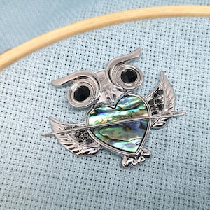 May include: Silver owl brooch with black rhinestones and a green and blue abalone shell heart.
