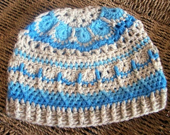 May include: A crocheted hat with a blue and beige color pattern. The hat has a textured design and a wide brim.