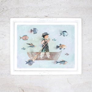 May include: A framed watercolour print shows a person rowing a boat surrounded by colourful fish. The person wears a hat and patterned clothing. The background is pale blue with fish and bone motifs. The frame is white.