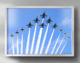 Puede incluir: Una fotografía enmarcada de un grupo de aviones de combate azules y blancos volando en formación, dejando estelas de humo blanco en un cielo azul claro.