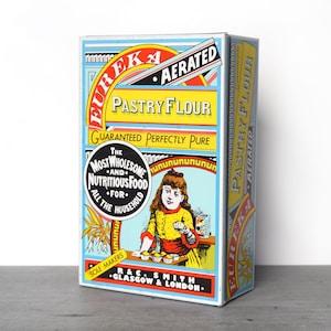 May include: A vintage tin box for Eureka Aerated Pastry Flour. The box is blue and yellow with a red and white label. The label features a young girl baking cupcakes and the text "The Most Wholesome and Nutritious Food for All the Household".