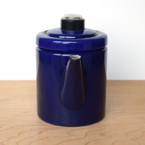 K&ouml;nnte beinhalten: Eine blaue Emaille-Kaffeekanne mit schwarzem Deckel und silbernem Ausguss.