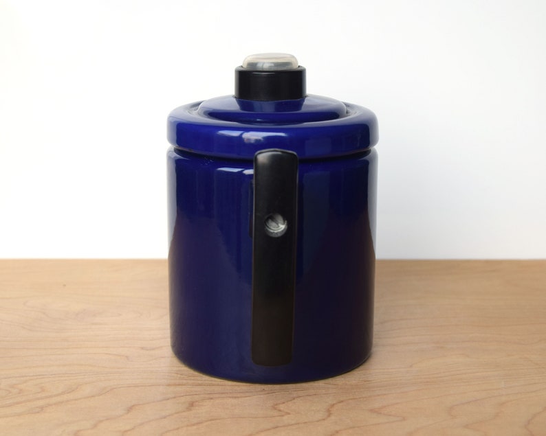 K&ouml;nnte beinhalten: Eine blaue Kaffeekanne aus Keramik mit einem schwarzen Griff und einem Deckel. Die Kanne hat ein schlichtes, klassisches Design.