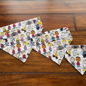 Dog bandana neckerchief, over the collar style. In Peanuts Cartoon fabric featuring Charlie Brown, Snoopy and Friends. Small, Medium, Large.