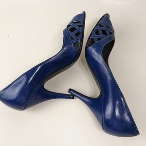 May include: A pair of blue leather peep-toe heels with a criss-cross design on the front. The heels are about 4 inches tall.