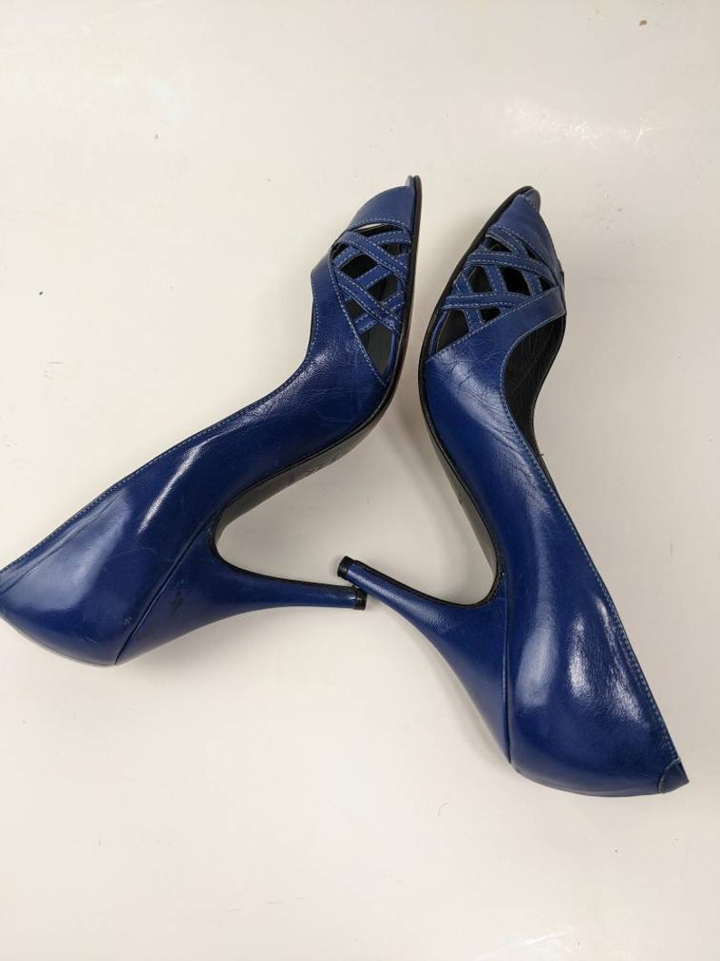 May include: A pair of blue leather peep-toe heels with a criss-cross design on the front. The heels are about 4 inches tall.