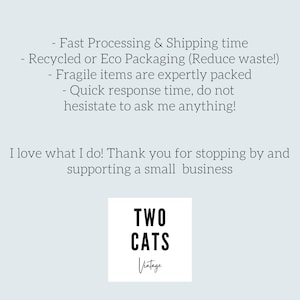 May include: A white square with black text that reads "TWO CATS Vintage". The text is in a bold, sans-serif font. The text is centered on the square.
