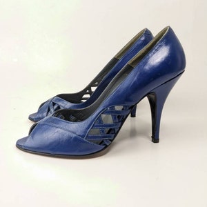 May include: A pair of blue leather peep-toe heels with a criss-cross design on the vamp. The heels are high and stiletto.