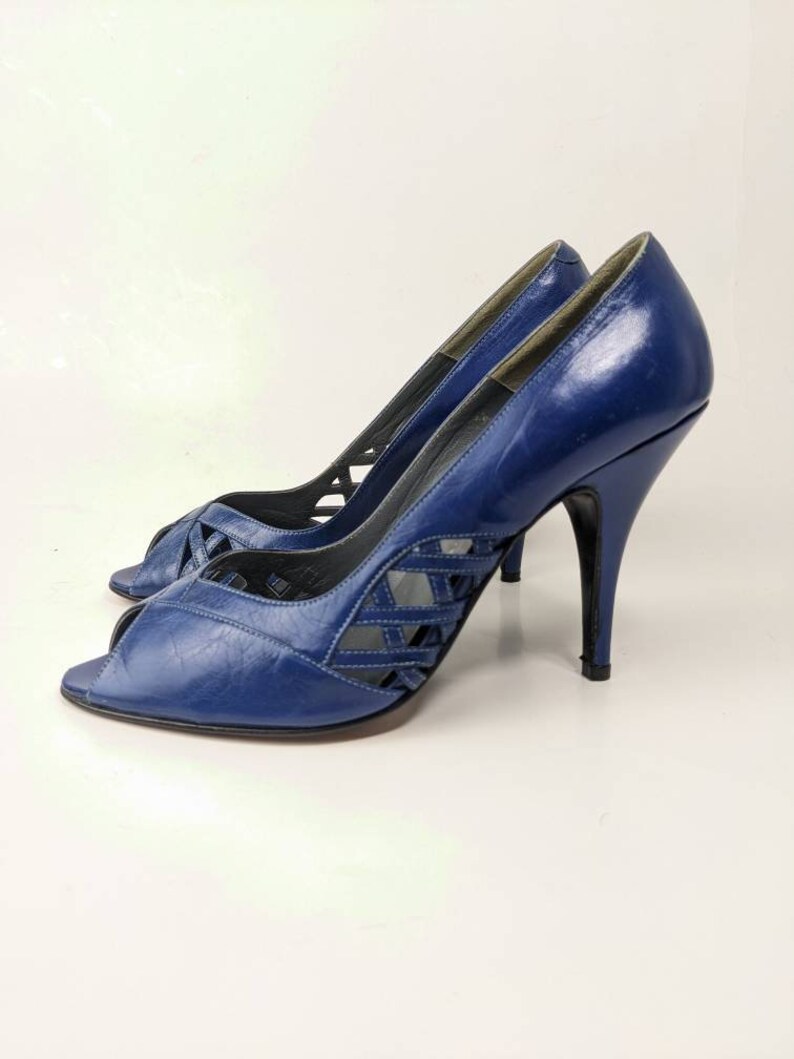 May include: A pair of blue leather peep-toe heels with a criss-cross design on the vamp. The heels are high and stiletto.