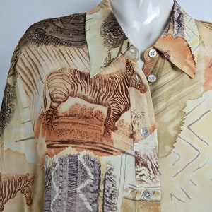 Peut inclure: Une chemise boutonnée beige à manches courtes avec un imprimé intégral de zèbres, d'arbres et de motifs abstraits en brun, beige et blanc.