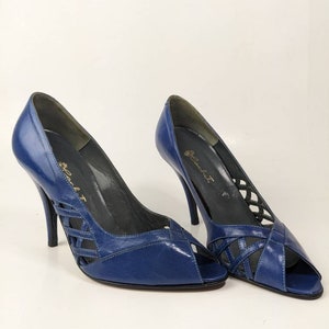 May include: A pair of blue leather peep-toe heels with a criss-cross design on the vamp. The heels are stiletto and the shoes are labeled "Belladonna".