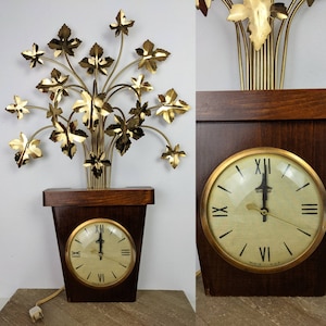 May include: A vintage wall clock with a gold metal leaf design. The clock is in a dark wood frame and has a white face with black Roman numeral markings. The clock is plugged in and has a cord hanging down.
