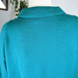 May include: A teal blue knitted sweater with a ribbed collar.