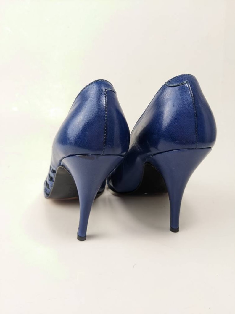 May include: A pair of blue leather high-heeled shoes with a cut-out design on the sides.