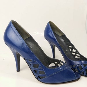 May include: A pair of blue leather peep-toe heels with a criss-cross design on the vamp and a stiletto heel.