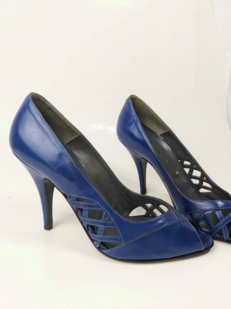 May include: A pair of blue leather peep-toe heels with a criss-cross design on the vamp and a stiletto heel.