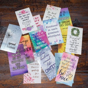 May include: A collection of colorful cards with inspirational quotes about kindness. The cards feature watercolor backgrounds and handwritten text. Some of the quotes include "Spread kindness", "Kindness is one's greatest attribute", and "Throw kindness around like confetti".