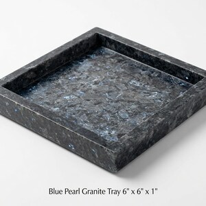 May include: A square Blue Pearl granite tray measuring 6 inches by 6 inches by 1 inch. The tray features a dark, polished stone surface with natural crystalline flecks in shades of blue, gray, and black, with raised edges and a flat base.
