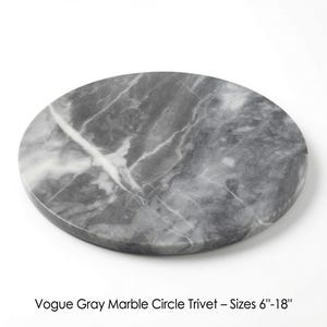 Può includere: Un sottopentola circolare in marmo grigio con venature bianche. La superficie presenta un motivo in pietra naturale con varie tonalità di grigio. Il testo sotto l'oggetto recita: Vogue Gray Marble Circle Trivet – Sizes 6"-18".