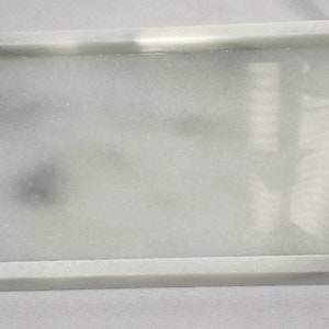 May include: A white rectangular tray with a raised rim. The tray has a subtle marbled pattern with gray streaks throughout.