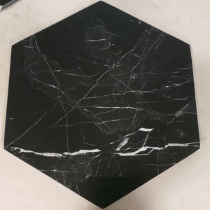 May include: Black hexagonal tile with white veining. The tile has a smooth, polished surface.