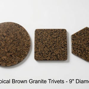 Op de afbeelding: Drie onderzetters van tropisch bruin graniet in ronde, vierkante en zeshoekige vormen. Elk stuk heeft een gespikkeld bruin en zwart steenpatroon. De tekst hieronder luidt: Tropical Brown Granite Trivets - 9" Diameter.