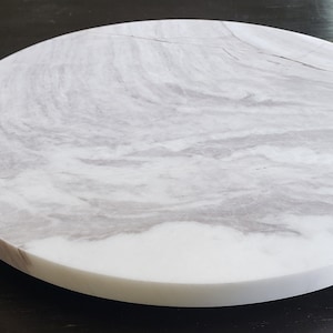 May include: A round white marble serving tray with grey veining. The tray is approximately 30 cm in diameter.