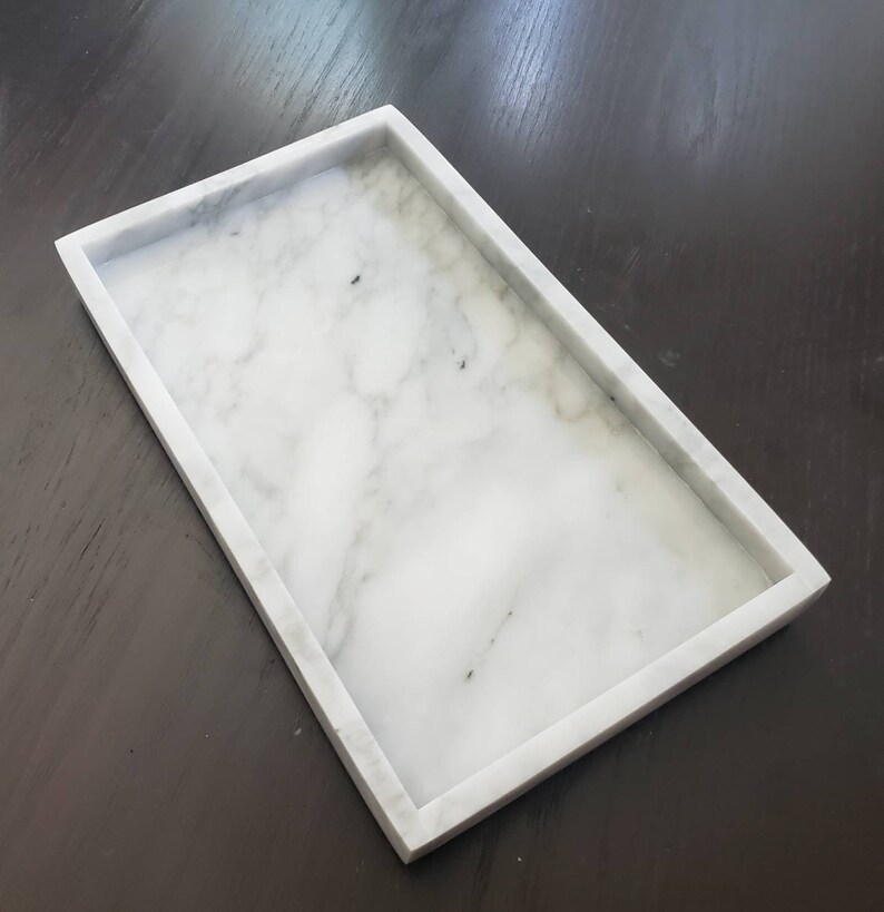 May include: A white marble rectangular tray with a smooth surface and slightly raised edges.