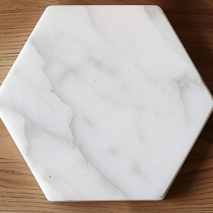 May include: White hexagonal marble coaster with a veined pattern.