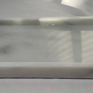 May include: A white rectangular tray made of marble with a smooth, polished surface.