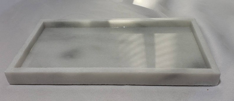May include: A white rectangular tray made of marble with a smooth, polished surface.