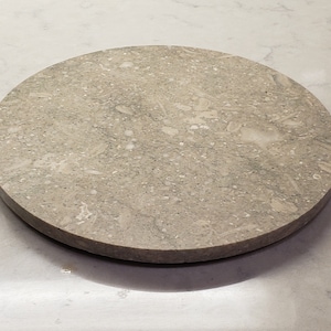 May include: A round, light grey, speckled, stone coaster.