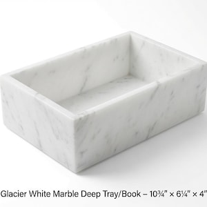 Puede incluir: Una bandeja profunda rectangular hecha de mármol blanco glaciar con vetas grises. La bandeja cuenta con paredes altas y mide 27,3 cm por 15,9 cm por 10,2 cm. La superficie es lisa y pulida, mostrando el patrón natural de la piedra en el objeto.