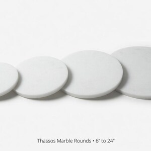 May include: Four white marble rounds of varying sizes are arranged in a row. The sizes range from 15 to 61 cm in diameter. The text "Thassos Marble Rounds" is at the bottom.