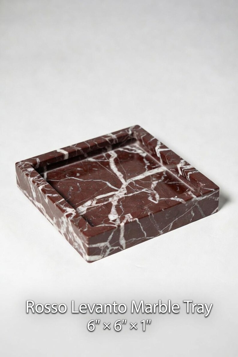 May include: A square Rosso Levanto marble tray featuring deep red tones with prominent white veining. The tray has a raised border and measures 6 inches by 6 inches by 1 inch as indicated by the text printed below the object in the image.