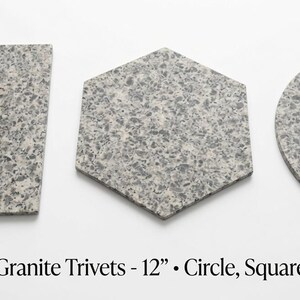 May include: Three Beige Mara granite trivets in square, hexagonal, and circular shapes. Each piece features a speckled grey and beige stone pattern. The text below reads: Beige Mara Granite Trivets - 12" • Circle, Square & Hexagon.