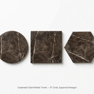 May include: Three Emperador dark marble trivets in circular, square, and hexagonal shapes. Each piece features a deep brown base with white veining. The text below reads: Emperador Dark Marble Trivets - 9" Circle, Square & Hexagon.
