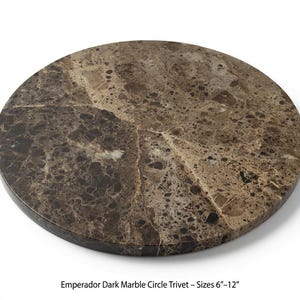 May include: A circular trivet made of Emperador dark marble featuring a polished surface with a complex pattern of brown, tan, and cream-coloured stone fragments. The text below the object reads: Emperador Dark Marble Circle Trivet – Sizes 6"–12".