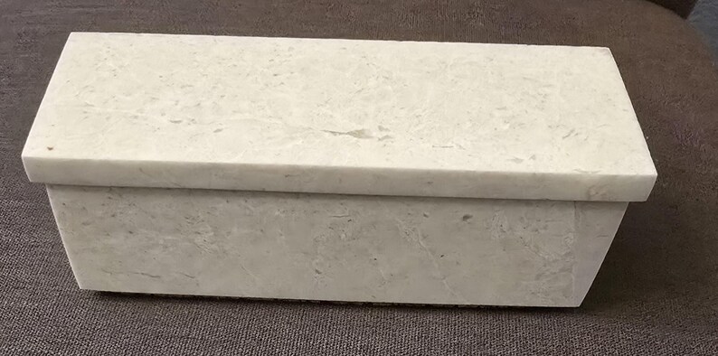 Puede incluir: Una caja rectangular blanca con una superficie texturizada. La caja est&aacute; hecha de un material que se asemeja al m&aacute;rmol.