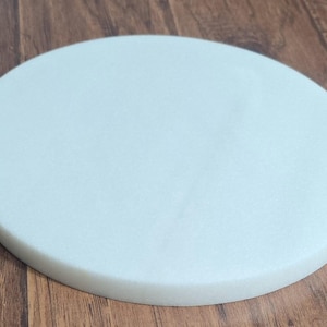 May include: A round, white, foam cake board.