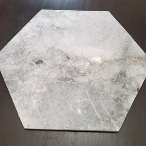 May include: A hexagonal grey and white marble tile with a light grey background and gold veining.