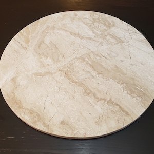 May include: A round, beige marble coaster with a light brown veined pattern.