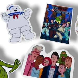 May include: A collection of colorful stickers featuring characters and imagery from the animated series "The Real Ghostbusters." Includes the Stay Puft Marshmallow Man, the Ghostbusters team, and other related characters. The stickers are white with colorful illustrations.