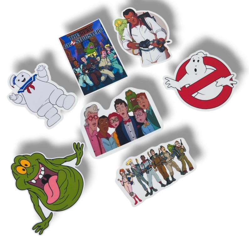 May include: A collection of colorful Ghostbusters-themed stickers. The stickers feature characters and logos from the movie, including the Stay Puft Marshmallow Man, Slimer, and the Ghostbusters logo. The stickers are on a white background.