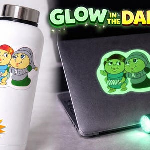 Puede incluir: Botella de agua blanca con una pegatina de dibujos animados de dos personajes. Un personaje viste un atuendo azul y el otro un atuendo gris. La pegatina brilla en la oscuridad. También se ve el texto "Lights On".