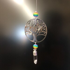 May include: A silver tree of life ornament with two butterflies, rainbow beads, and a small glass vial with a silver cap. The vial has the word "Live" written on it.